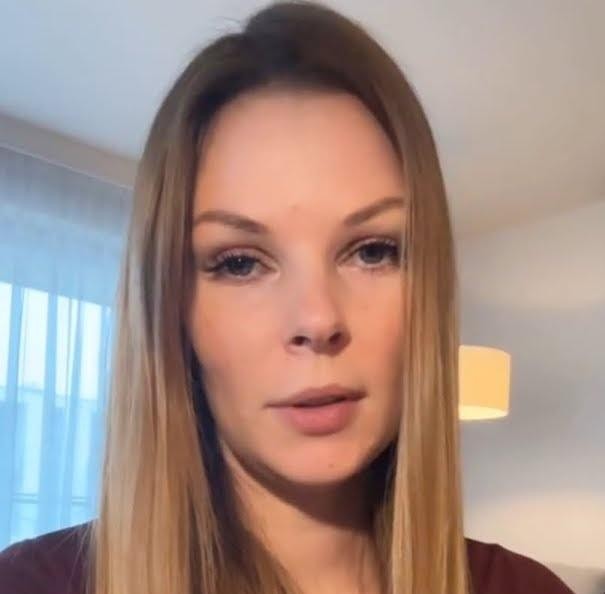 Małgorzata Tomaszewska w studio telewizyjnym, dynamicznie prowadząca program, w eleganckim stroju.