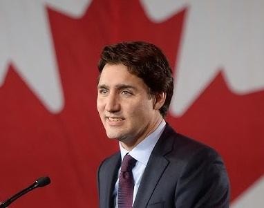 Justin Trudeau podczas publicznego wystąpienia, gestykulujący, w otoczeniu ludzi.