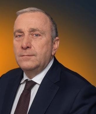 Grzegorz Schetyna podczas spotkania politycznego, aktywnie gestykulujący, w tle logo Platformy Obywatelskiej.