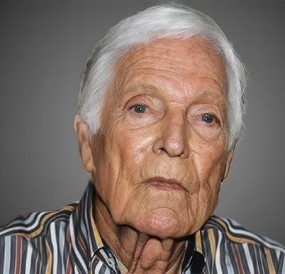 Richard Chamberlain jako ksiądz Ralph de Bricassart z miniserialu „Ptaki ciernistych krzewów” w charakterystycznym stroju, na tle australijskiego krajobrazu.