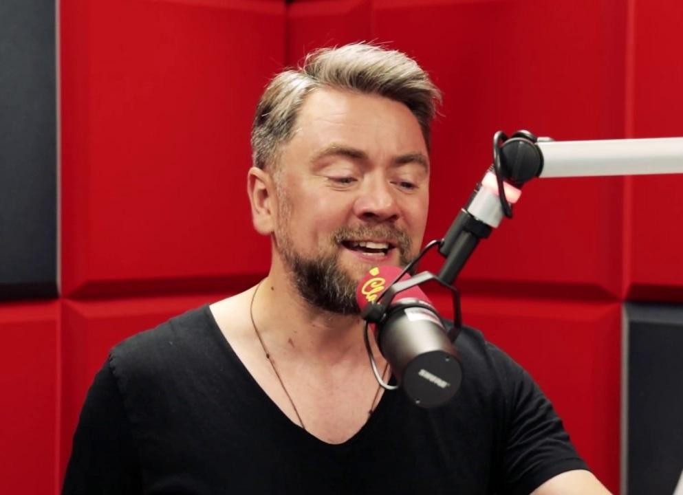 Kuba Badach podczas występu na żywo, śpiewający do mikrofonu na scenie.