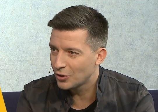 Michał Cessanis podczas dynamicznej prelekcji o podróżach, z ekranem w tle przedstawiającym krajobraz Australii Zachodniej.