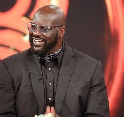 Shaquille O'Neal w koszulce Lakers świętujący mistrzostwo NBA, z konfetti i kolegami z drużyny w tle.