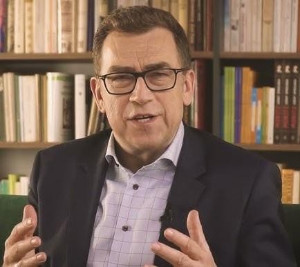 Maciej Orłoś przeglądający media społecznościowe na smartfonie, symbolizujący jego aktywność online.