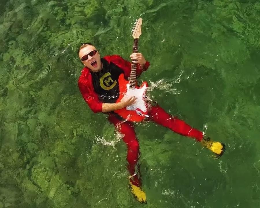 Czadoman podczas energicznego występu na scenie, otoczony kolorowymi światłami, w trakcie koncertu.