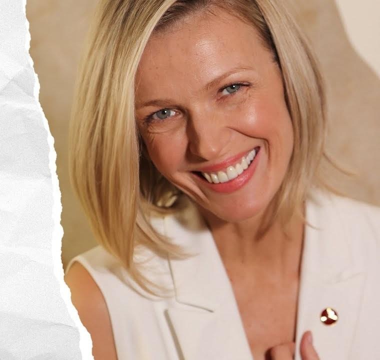 Magda Mołek w eleganckim stroju w studiu telewizyjnym, emanująca profesjonalizmem i charyzmą.